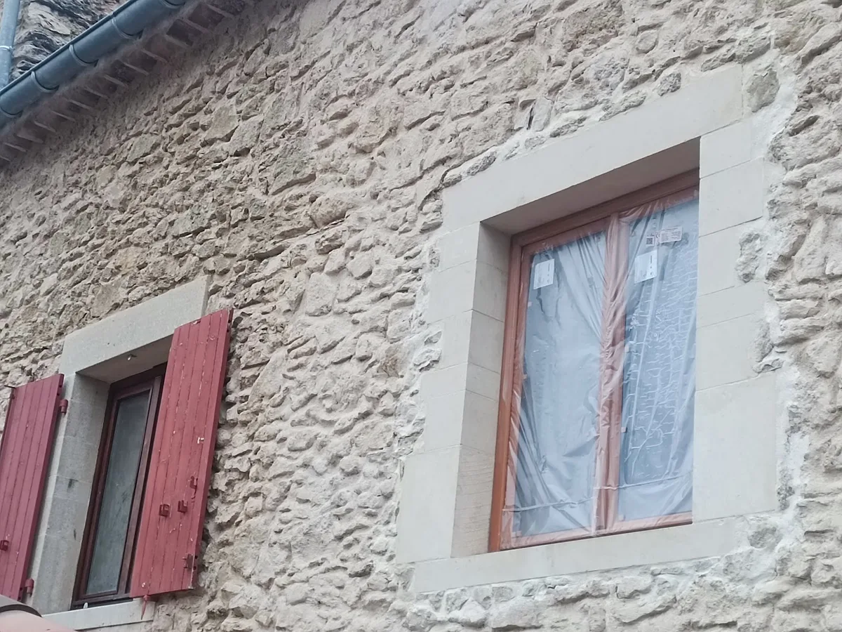Façade en pierre apparente rejointoyée, volets rouges