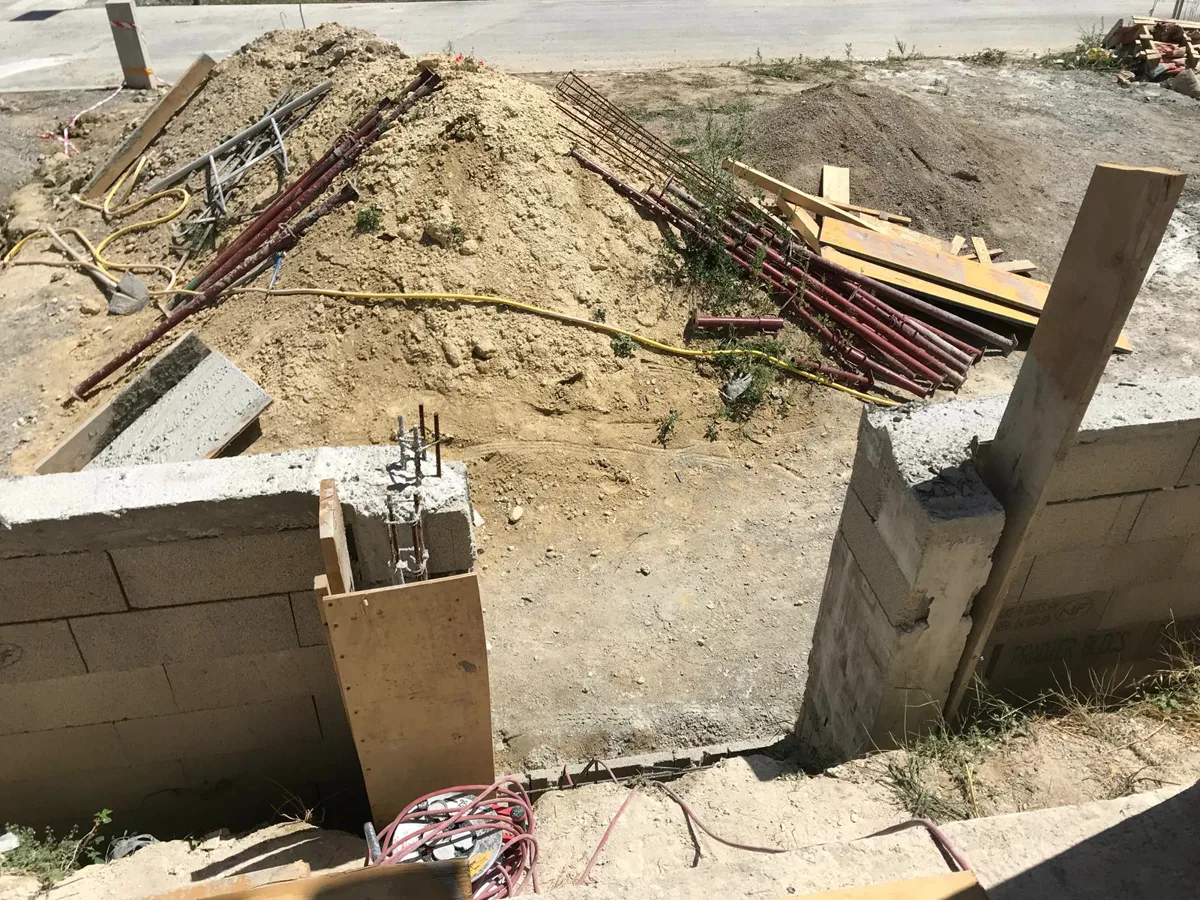 Chantier de gros œuvre avec ferraillage en attente et murs en pierre reconstituée