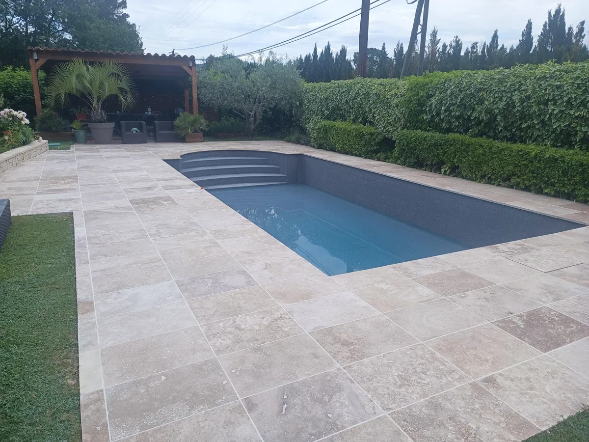 Piscine terminée entourée d'une plage en travertin